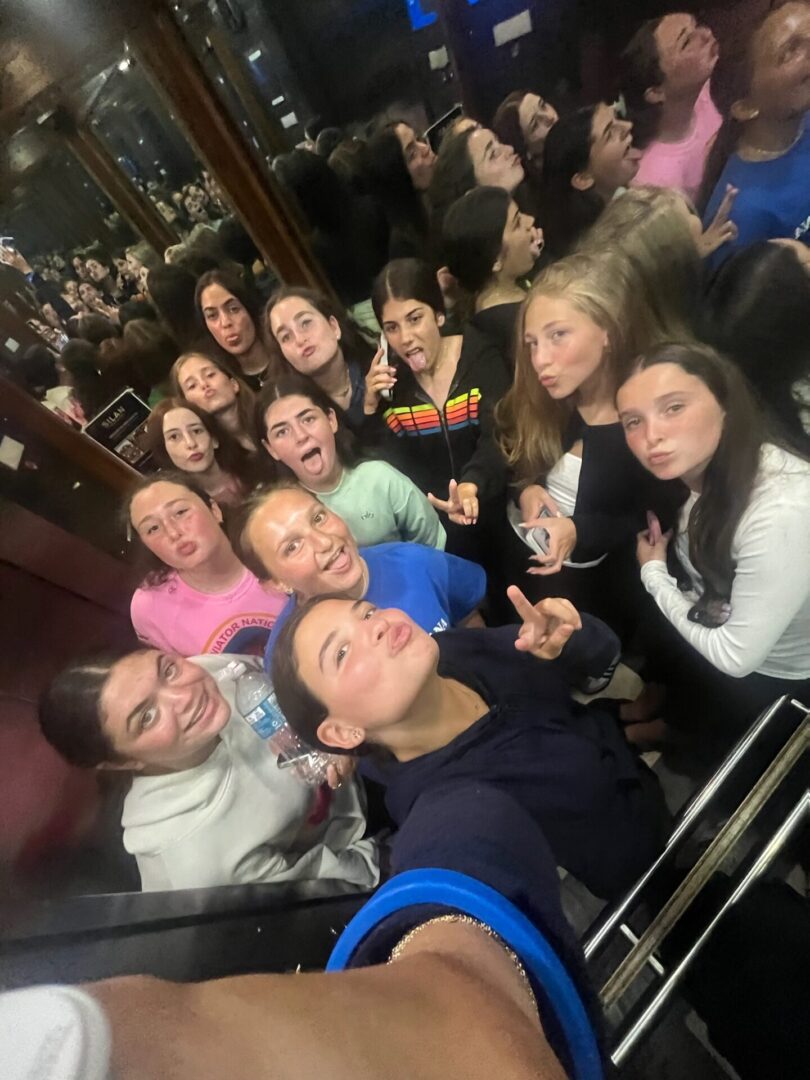 A group selfie of smiling young people in an indoor setting.