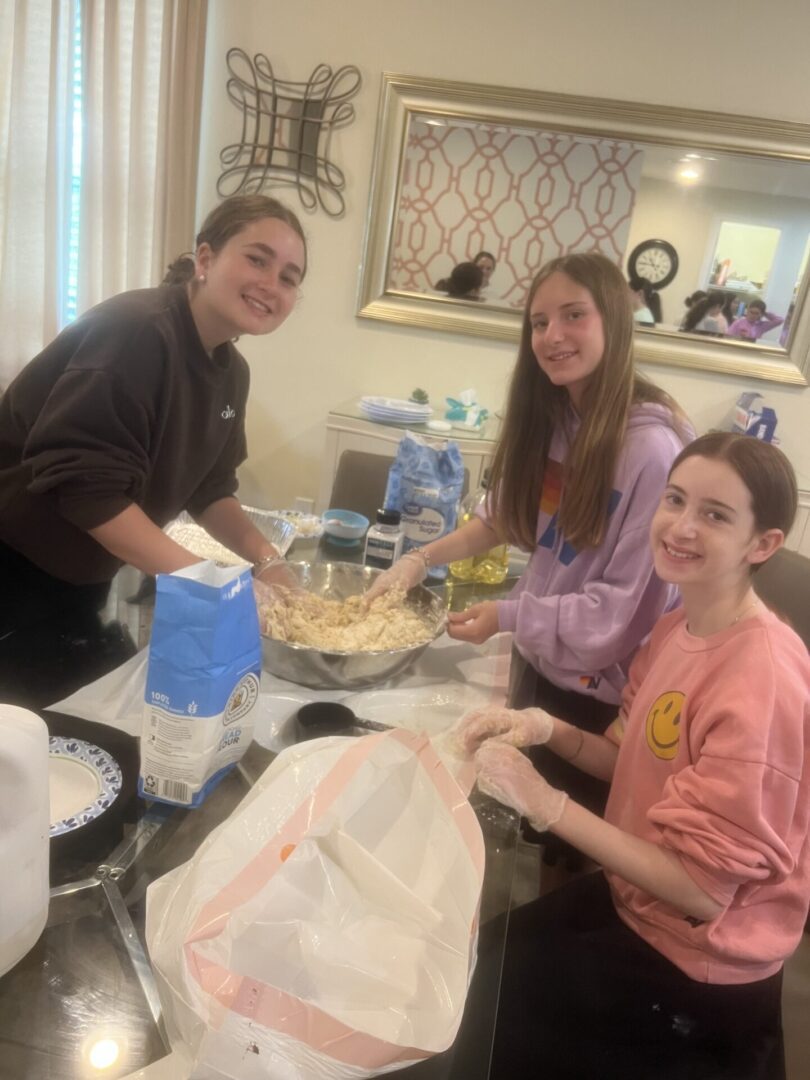 Three young people preparing food together in a kitchen.