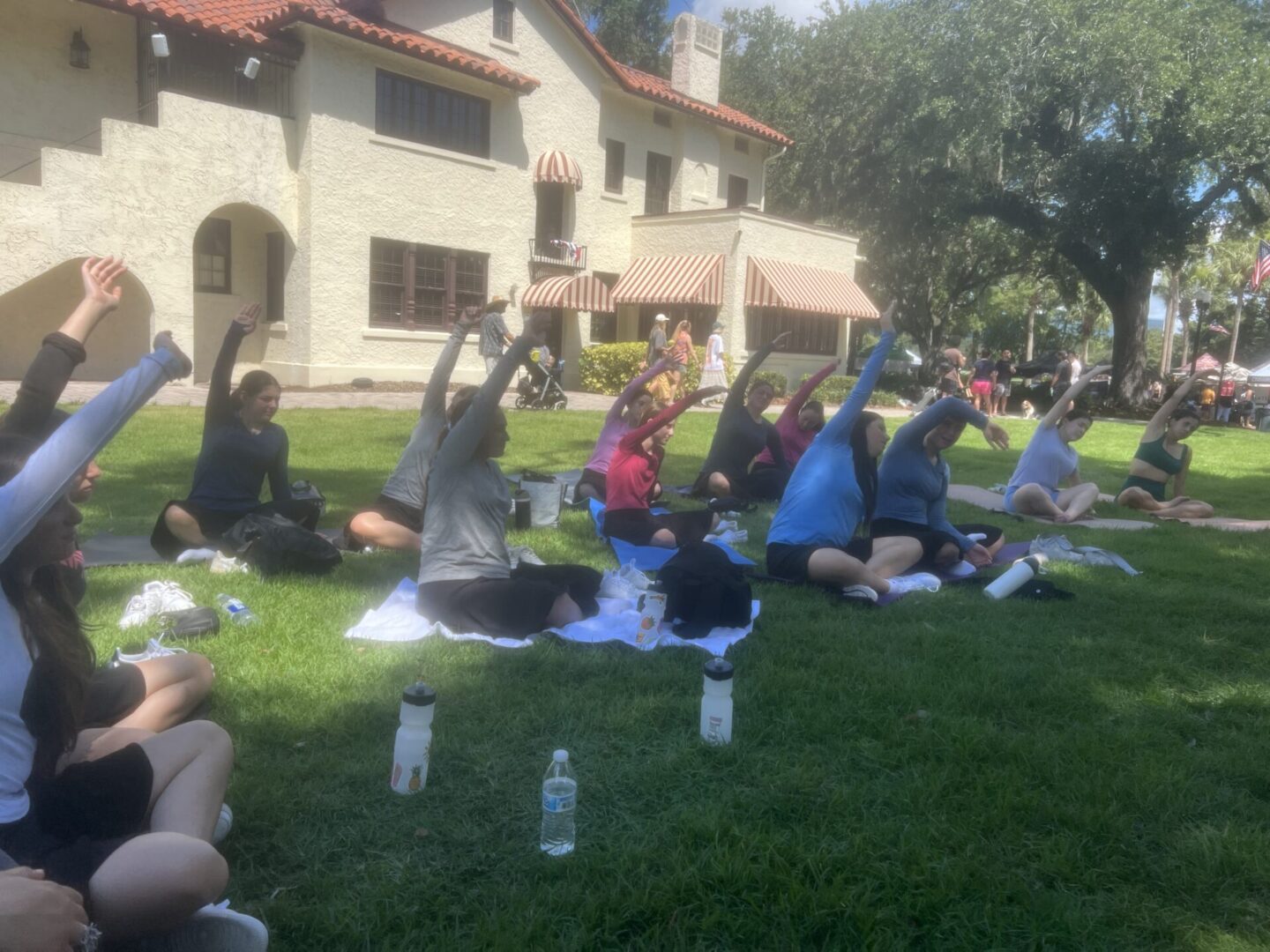 Group of people practicing yoga outdoors on a sunny day.