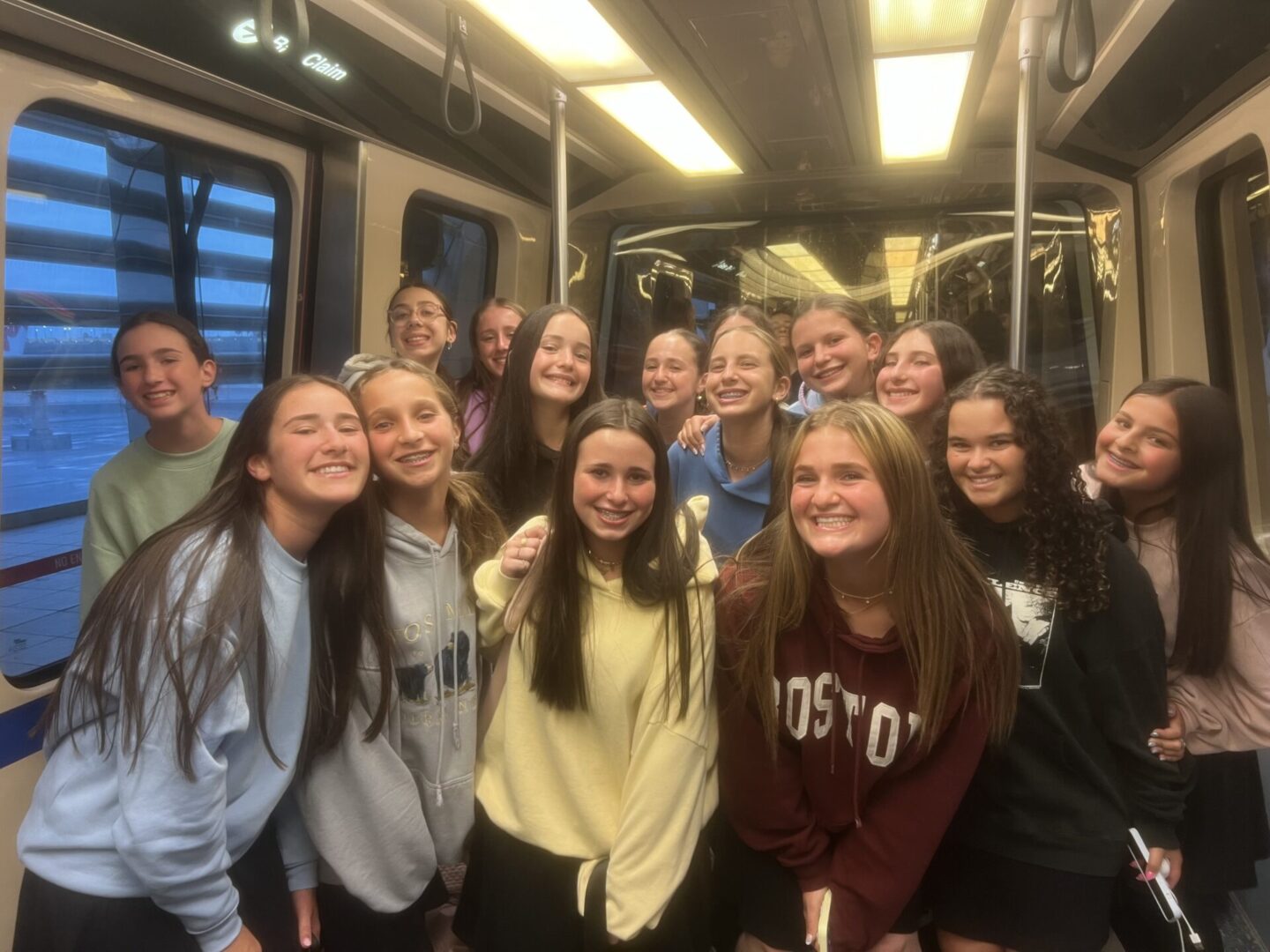 Group of smiling young women posing inside a bus or tram.