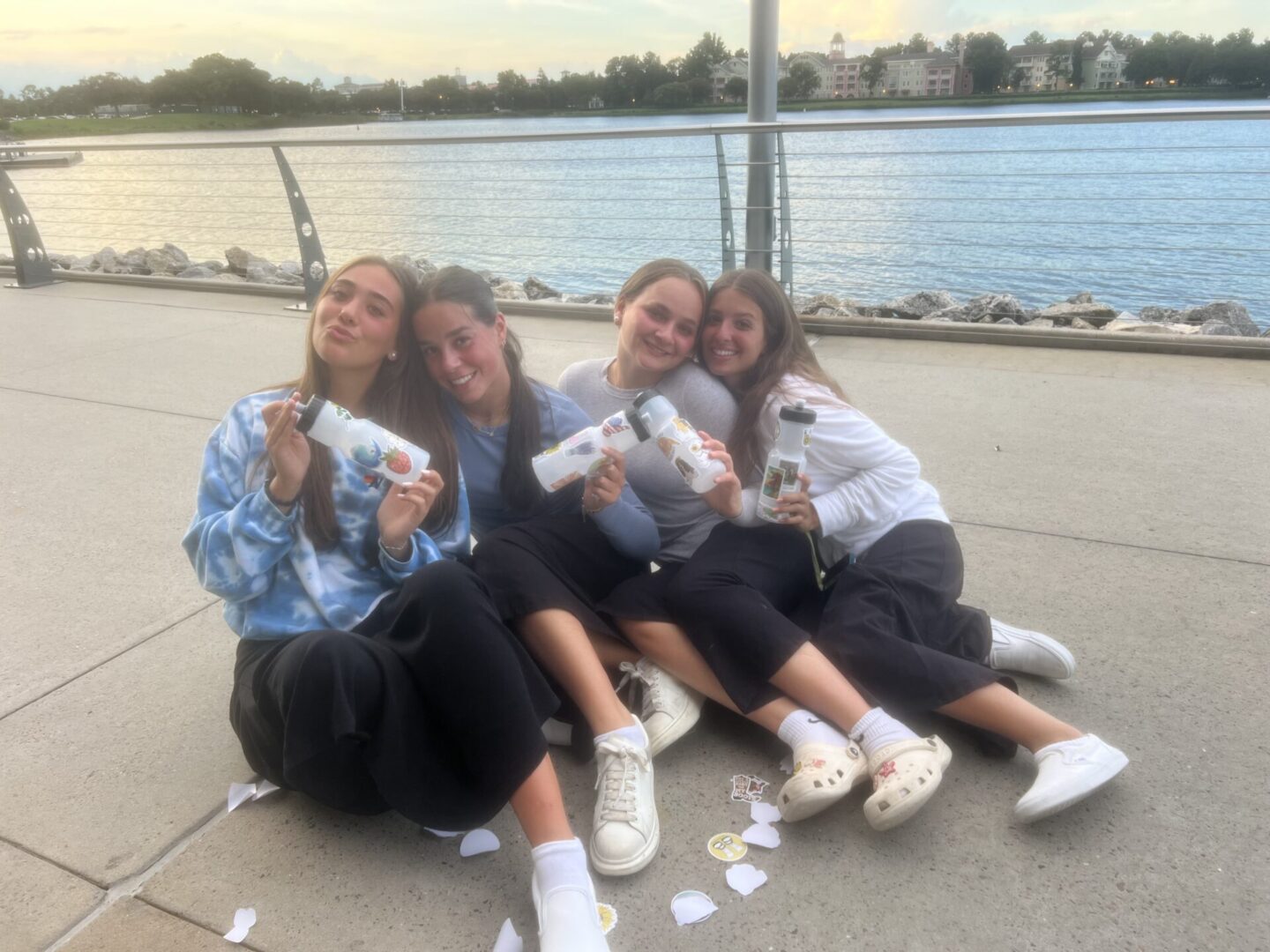 Four friends sitting by the water, sharing smiles and ice cream cones.