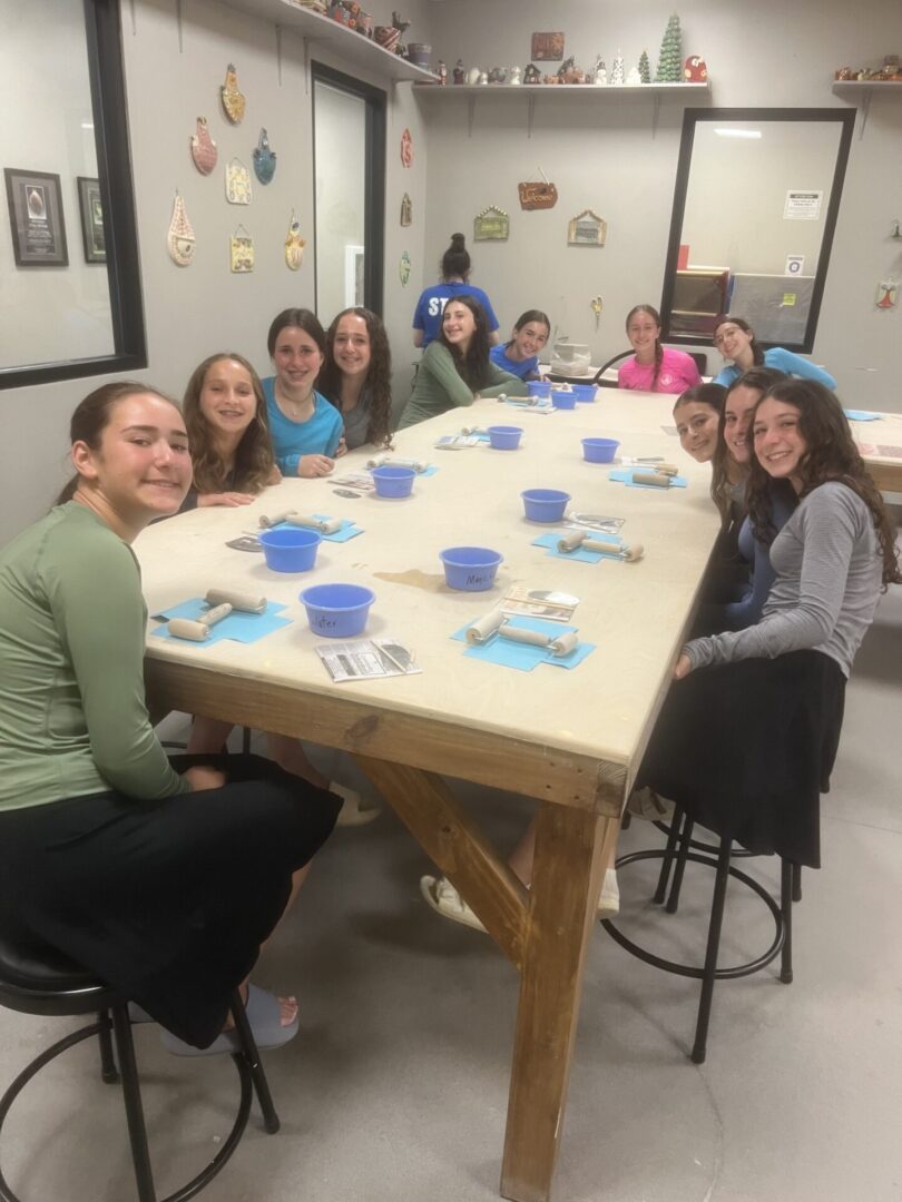 A group of young women sitting around a table with art supplies.