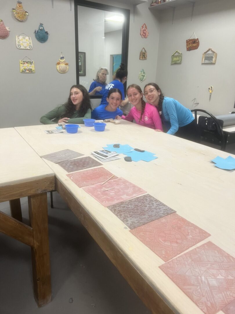 Four women smiling and sitting around a table with fabric swatches.
