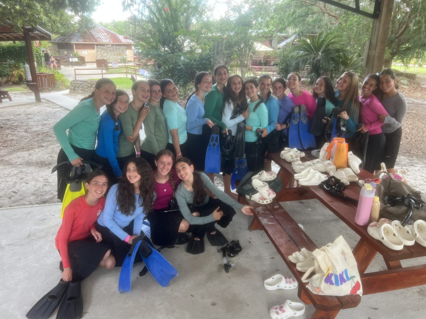 Group of people posing outdoors around a picnic table.