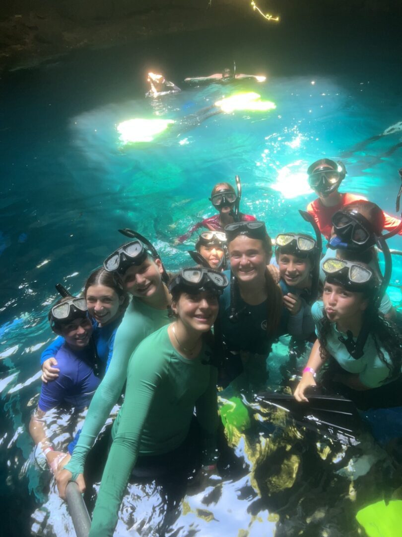 Group of friends snorkeling in clear blue water under sunlight.