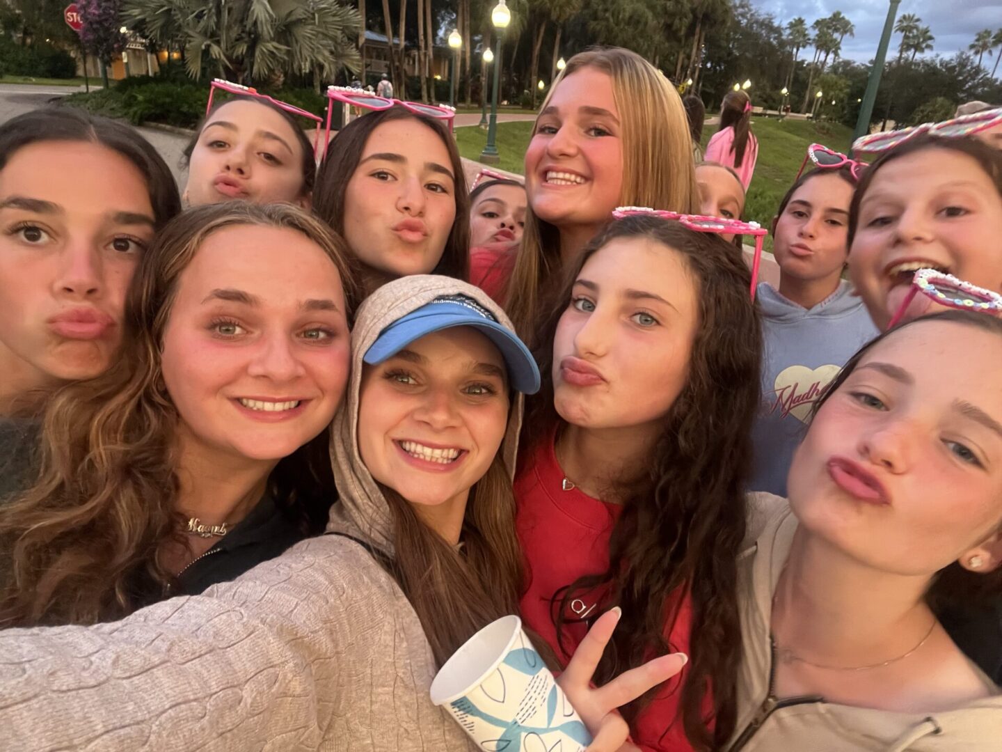 Group of young women smiling and posing for a selfie outdoors.