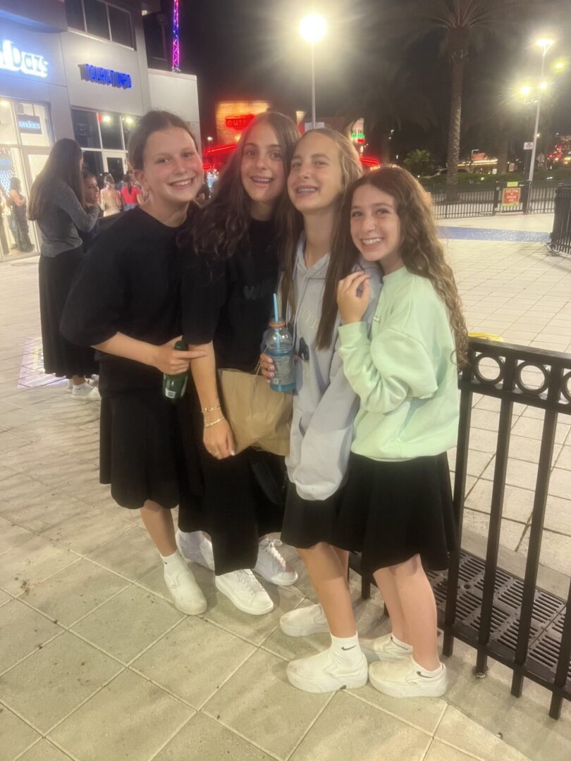 Three girls smiling together outdoors at night.