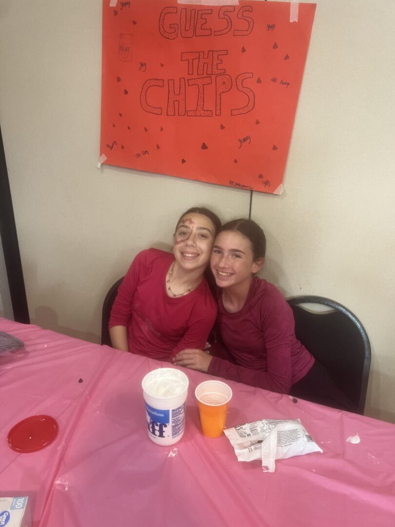 Two girls smiling together at a pink-themed party table.