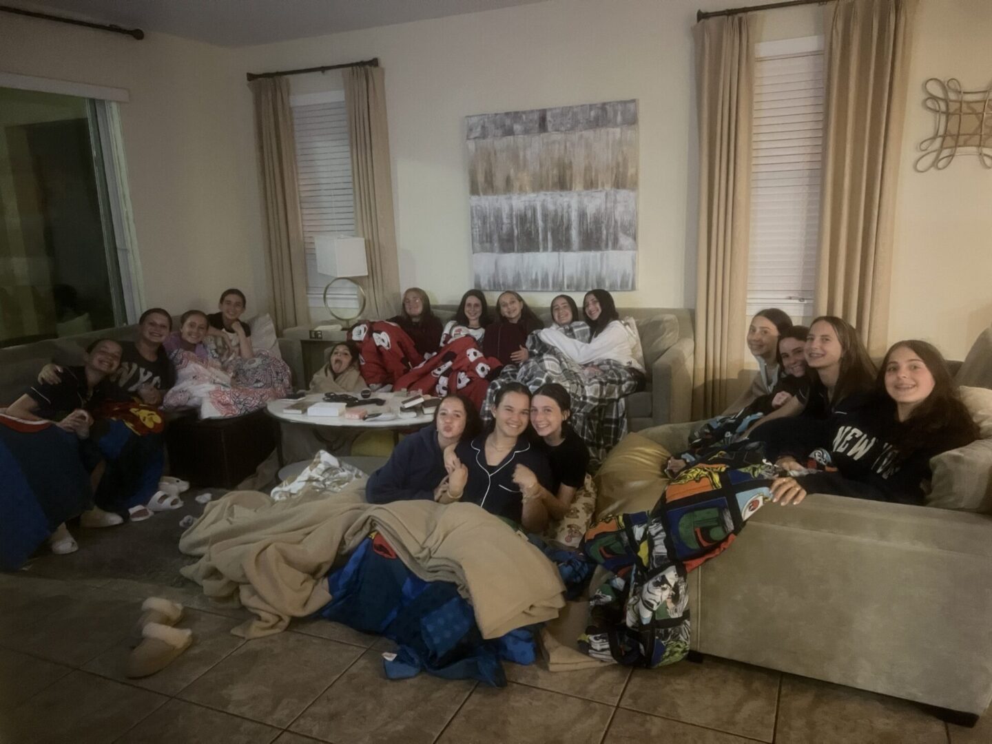 Group of young people gathered in a cozy living room, some in pajamas.