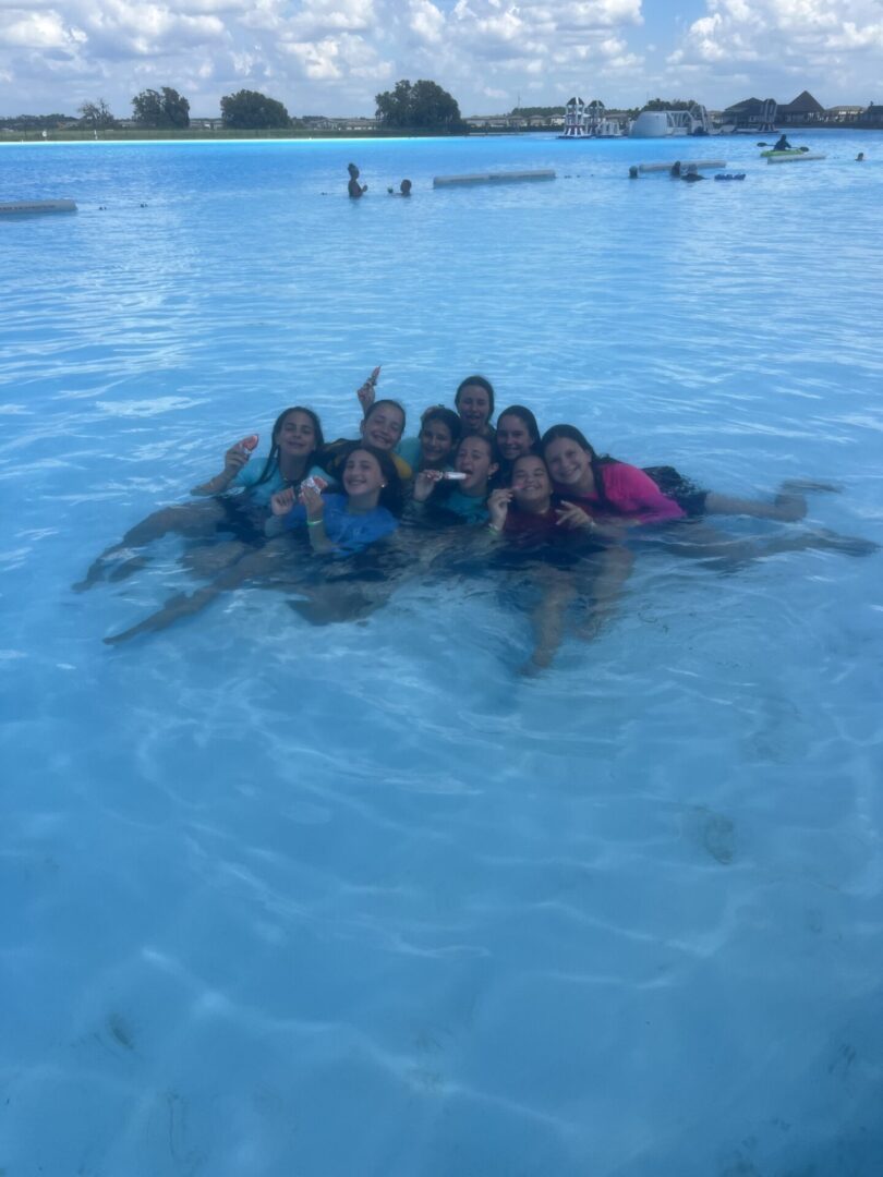 Group of friends enjoying a swim in clear blue water.