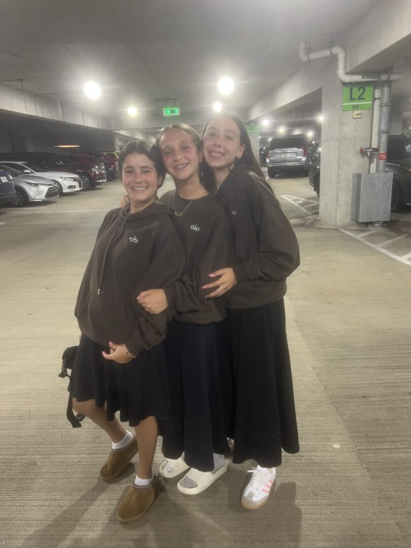 Three friends smiling together in a parking garage.