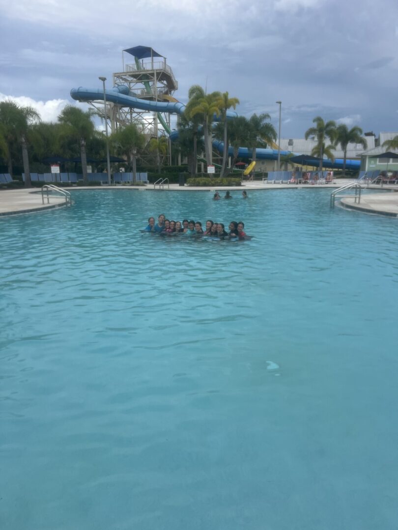 People enjoying a sunny day in a large outdoor swimming pool.