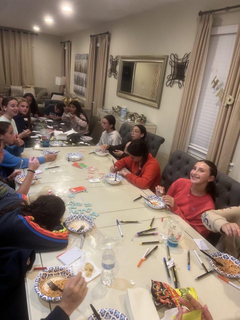 Children engaged in a creative craft activity around a long table.
