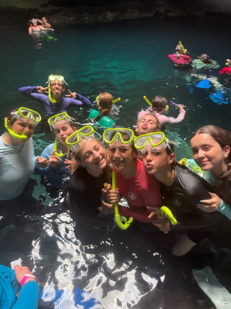 Group snorkeling session with smiles and colorful gear in the water.