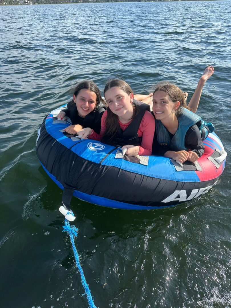 Three people enjoying a water tube ride on a lake.